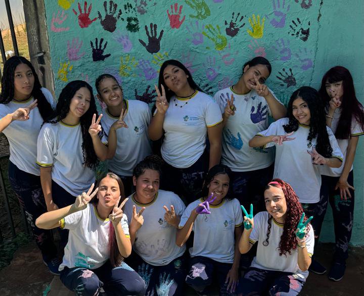 Estudantes do CEPI Novo Horizonte reunidas em frente ao mural de mãos coloridas do projeto